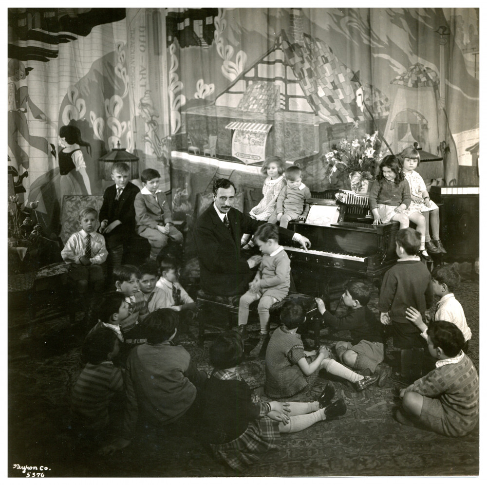 Photographie du pianiste, compositeur et chef d'orchestre américain d'origine suisse Ernest Schelling entouré d'enfants (futurs mélomanes?) autour de son piano, sans doute en lien avec les «Young People's Concerts» du New York Philharmonic qu'il a fondés