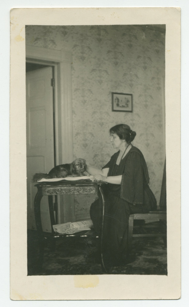 Photographie d'Hélène Paderewska carressant son chien Ping, installé sur une table dans sa chambre à coucher de Riond-Bosson