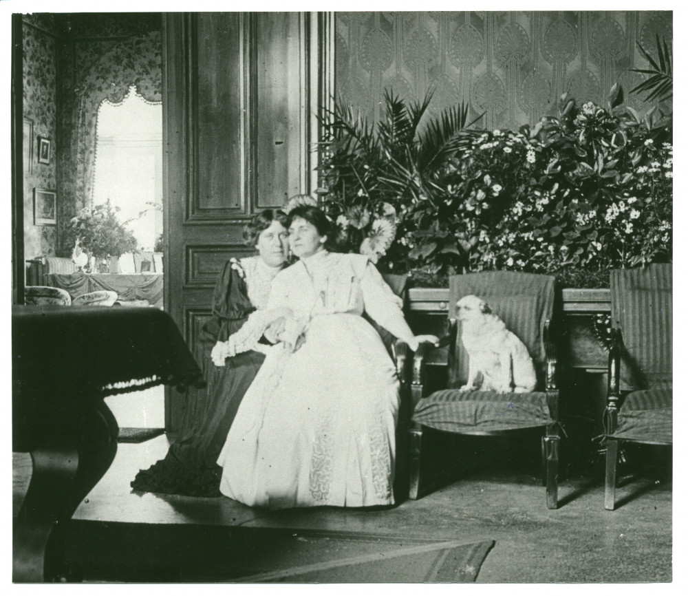 Photographie d'Hélène Paderewska assise dans le hall de Riond-Bosson avec une inconnue (Mme Obuchowicz?) et sa chienne Manon