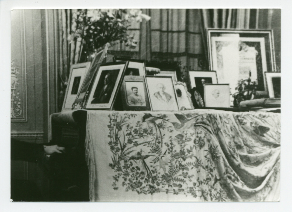 Photographie de détail d'un piano à queue du salon de Riond-Bosson, avec exposées dessus de nombreuses photos dédicacées et les mains de Paderewski sur le clavier