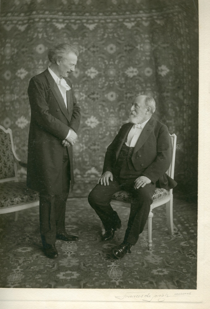 Photographie de Camille Saint-Saëns (assis) et Paderewski (debout) face-à-face, réalisée dans les salons de l'Hôtel des Trois Couronnes à Vevey dans le cadre des Fêtes musicales données du 18 au 21 mai 1913 en l'honneur de Camille Saint-Saëns