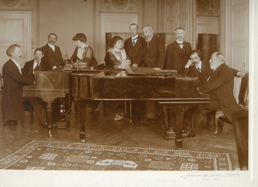 Photographie signée de Francis de Jongh représentant Paderewski et Camille Saint-Saëns face-à-face au piano dans les salons de l'Hôtel des Trois Couronnes à Vevey dans le cadre des Fêtes musicales données du 18 au 21 mai 1913 en l'honneur de Camille Saint-