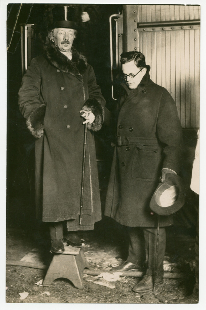 Photographie de Paderewski (sur une escabelle – devant un wagon de chemin de fer?) à l'époque de la Conférence de paix de Paris en 1919 (avec un jeune homme à lunettes à ses côtés)