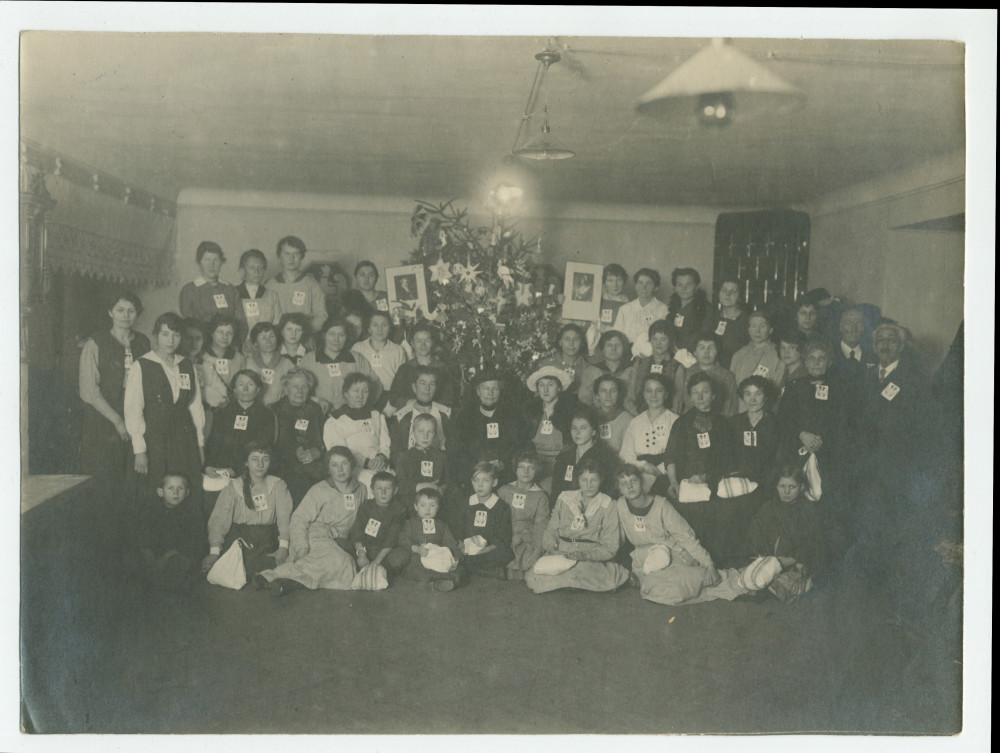 Photographie de groupe (enfants et adultes munis de l'écusson de la Croix Blanche polonaise) à l'occasion d'une fête de Noël organisée le 21 décembre 1920 au numéro 1 de la rue Sikorski (ville?) en hommage (?) à Hélène Paderewska
