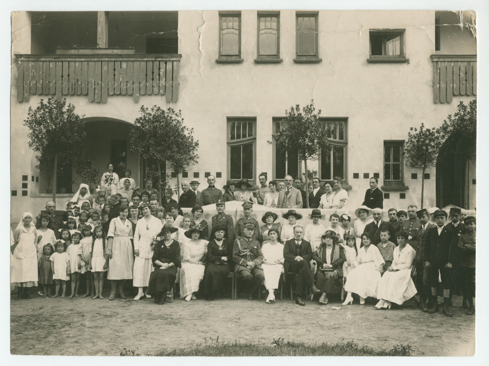 Photographie de groupe devant une école de la Croix Blanche polonaise, avec au centre Mme Rembielinska (fidèle collaboratrice des œuvres de charité d'Hélène Paderewska) et des officiers polonais, en juin 1921