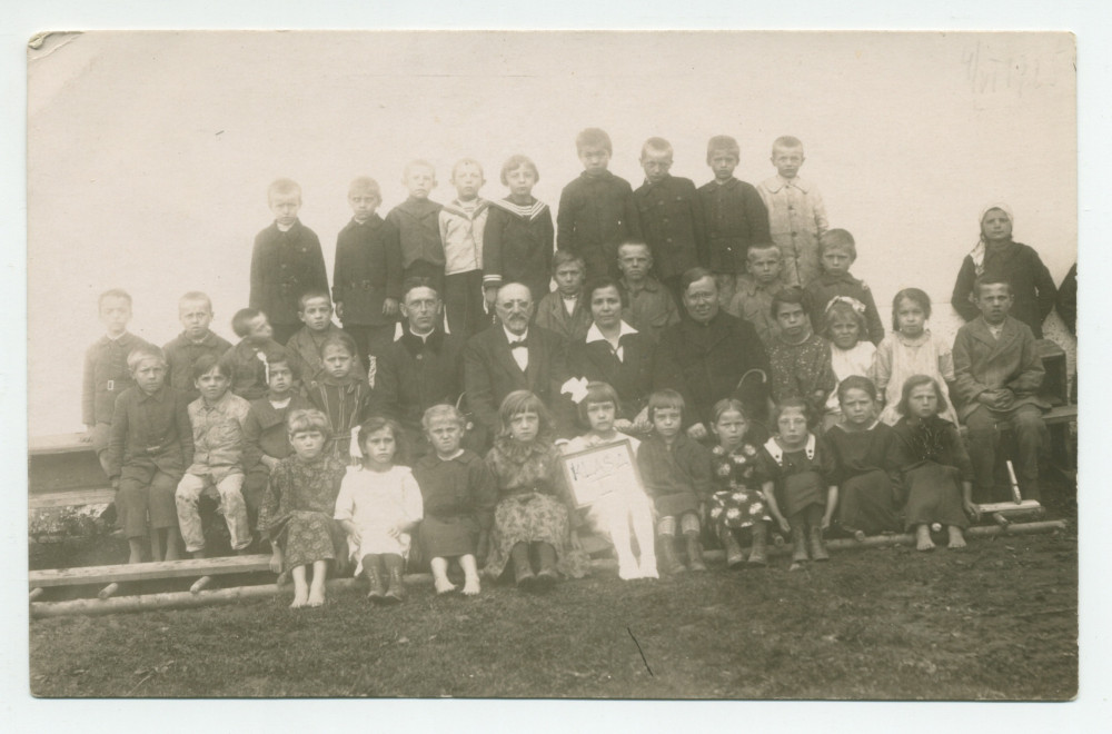 Photographie d'une classe de première année (sans doute financée par la Croix Blanche polonaise) avec enseignants, en 1925 – avec légende manuscrite difficile à lire au verso («Madame Moriwe à Deblin?)