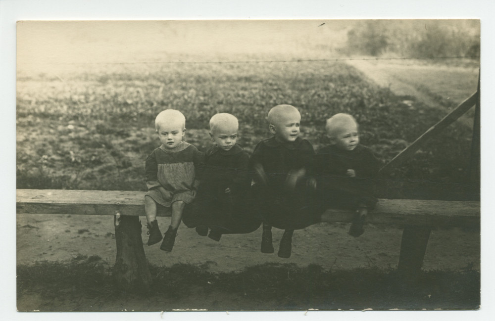 Photographie de quatre jeunes enfants, crâne rasés, souffrant manifestement de malnutrition, pris en charge par la Croix Blanche polonaise – tirage carte postale