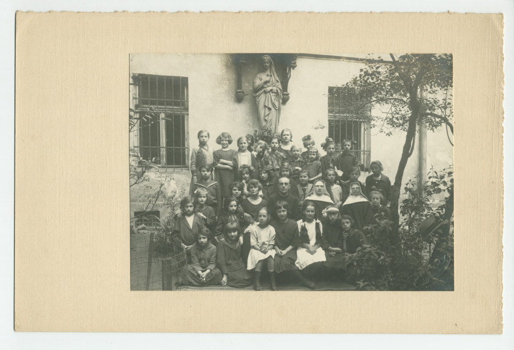 Photographie d'une classe de filles de cinquième année (sans doute financée par la Croix Blanche polonaise) avec enseignants (religieux) – avec signatures de toutes les élèves et tampon du photographe au verso
