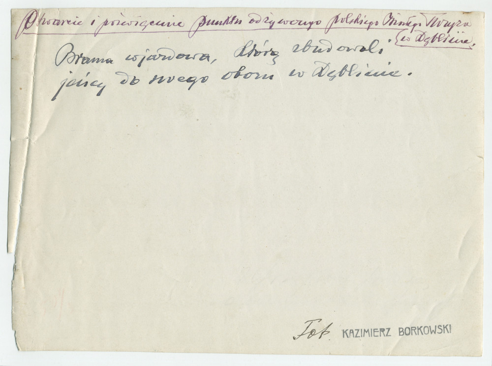 Photographie du panneau de bienvenue réalisé par des prisonniers de guerre au point d'alimentation de la Croix Blanche polonaise à Deblin, ville de la voïvodie de Lublin, dans l'est de la Pologne – avec légende manuscrite et nom du photographe au verso