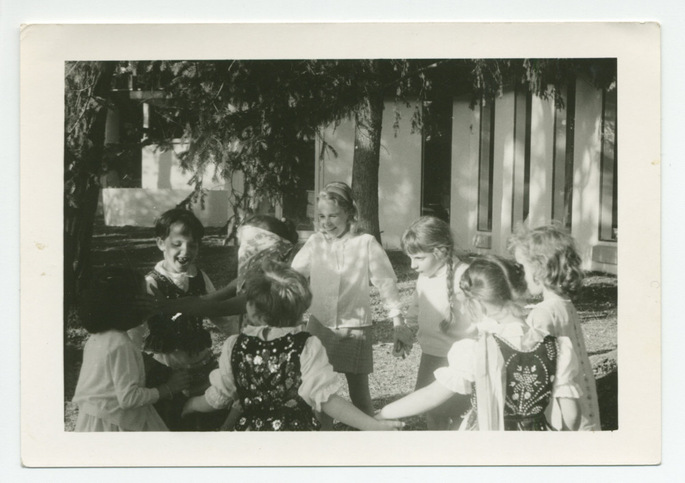 Photographie d'enfants en costume traditionnel polonais faisant une ronde dans un jardin (sans doute d'un centre d'hébergement de la Croix Blanche polonaise)