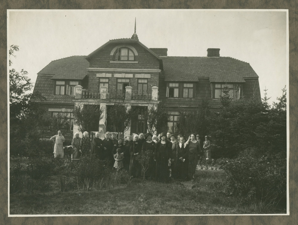 Photographie d'Hélène Paderewska devant une maison en compagnie sans doute de femmes bénévoles de la Croix Blanche polonaise