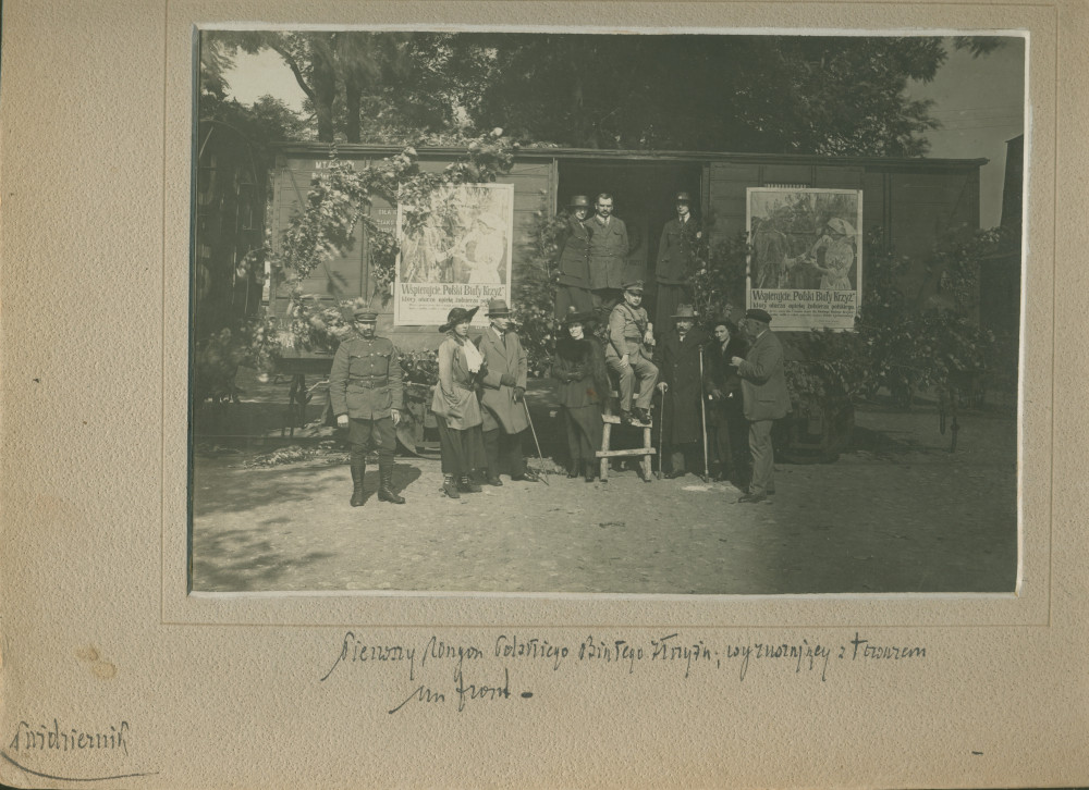 Photographie de militaires, infirmières et civils devant un wagon de la Première Légion de la Croix Blanche polonaise, placardé d'affiches de propagande, lors d'une collecte de dons pour le front (polono-lituanien?) en octobre (1920?)