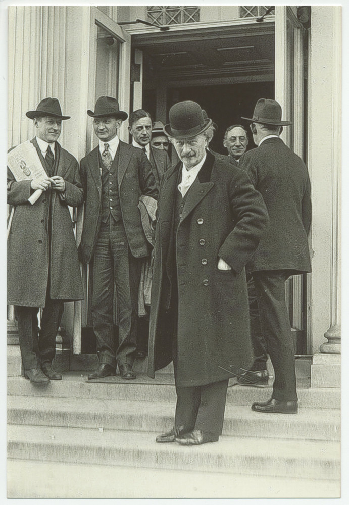 Photographie d'Ignace Paderewski avec son chapeau melon noir, de plein pied sur des escaliers, avec d'autres messieurs en arrière-plan, sans doute aux Etats-Unis dans les années 1920