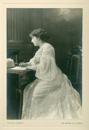 Photographie d'Hélène Paderewska en robe blanche, assise de profil écrivant, par The Falk Studios, Sydney, en 1904