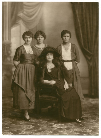 Photographie d'Hélène Paderewska en 1923, avec chapeau noir et collier de perles, assise entourée de trois jeunes femmes dont sa secrétaire Mlle Hélène Lübke (debout au milieu)