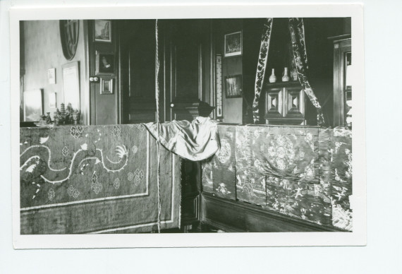 Photographie d'un coin de la galerie du 2e étage de Riond-Bosson, avec draperies et objets chinois, et au fond la porte menant à l'escalier de service