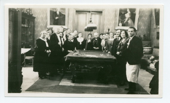 Photographie de Paderewski distribuant des cadeaux aux employés de Riond-Bosson autour de la table de billard, dans le hall, avec en arrière-fond les portraits d'Ignace et de Hélène Paderewski par Charles Giron, lors du réveillon 1930