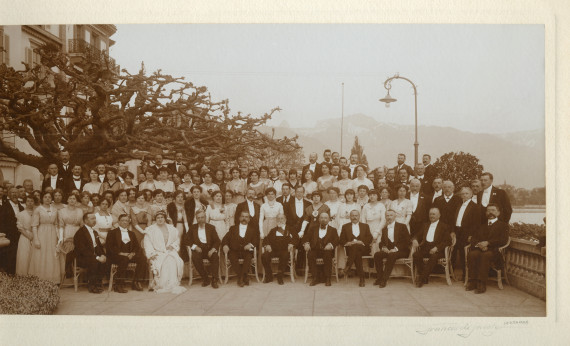 Photographie de groupe (en tenue de soirée), avec Camille Saint-Saëns assis au centre, réalisée sur la terrasse de l'Hôtel des Trois Couronnes à Vevey dans le cadre des Fêtes musicales données en mai 1913 en l'honneur de Camille Saint-Saëns