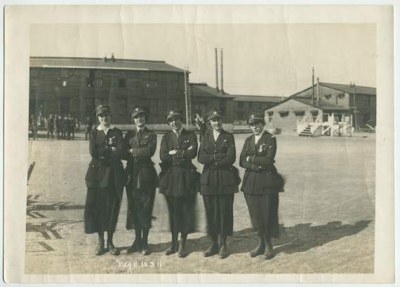 Photographie de cinq jeunes femmes en uniforme foncé avec casquette à l'effigie de la Croix Blanche polonaise
