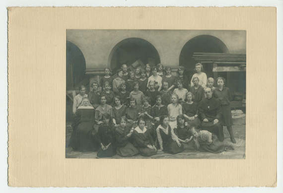 Photographie d'une classe de filles de septième année (sans doute financée par la Croix Blanche polonaise) avec enseignants (religieux) – avec signatures de toutes les élèves et tampon du photographe au verso