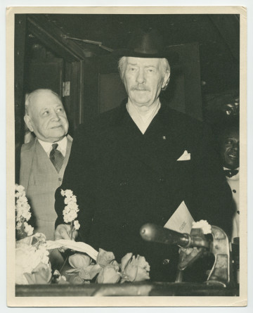 Photographie de Paderewski à l'arrière de son pullman-car privé (avec personnel de cabine), une fleur à la main, sous l'œil admiratif d'un homme non identifié, au début de son ultime tournée américaine en 1939