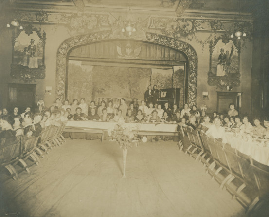 Photographie d'un repas de gala entièrement féminin aux couleurs américano-polonaises donné à Chicago en présence d'Hélène Paderewska (au centre à la table d'honneur) probablement à l'attention des bénévoles de de la Croix Blanche polonaise