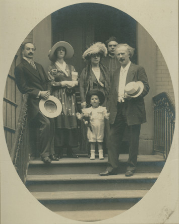 Photographie ovale d'Hélène et Ignace Paderewski sur un perron à New York (?) avec un enfant (à chapeau) tenant la main d'Ignace, un homme, une femme et un religieux en arrière-plan