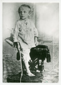 Photographie de pied du jeune Paderewski âgé d'environ 2 ans, sur une chaise avec une baguette dans la main droite (jeu?)