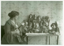 Photographie d'Hélène Paderewska dans sa chambre à coucher de Riond-Bosson avec une quinzaine de ses poupées confectionnées pour le Polish Victim's Relief Fund