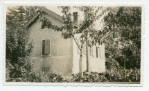 Photographie de la maison du gardien de Riond-Bosson derrière quelques arbres et une clôture