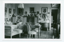 Photographie de la chambre à coucher d'Hélène Paderewska à Riond-Bosson, avec de nombreux encadrements et à droite la porte ouverte menant à la chambre à coucher de Paderewski