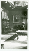 Photographie du hall de Riond-Bosson avec une vitrine, le billard et le portrait d'Ignace Paderewski par Charles Giron