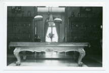 Photographie du hall de Riond-Bosson, prise depuis l'entrée principale, avec la table de billard et au fond la double-porte ouverte vers les salons
