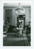 Photographie du salon de Riond-Bosson, prise depuis la salle à manger, avec au fond la porte menant au petit salon (dédié notamment au bridge)
