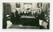 Photographie de Paderewski distribuant des cadeaux aux employés de Riond-Bosson autour de la table de billard, dans le hall, avec en arrière-fond les portraits d'Ignace et de Hélène Paderewski par Charles Giron, lors du réveillon 1930