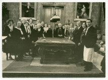 Photographie de Paderewski distribuant des cadeaux aux employés de Riond-Bosson autour de la table de billard, dans le hall, avec en arrière-fond les portraits d'Ignace et de Hélène Paderewski par Charles Giron, lors du réveillon 1930