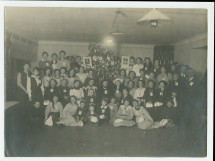 Photographie de groupe (enfants et adultes munis de l'écusson de la Croix Blanche polonaise) à l'occasion d'une fête de Noël organisée le 21 décembre 1920 au numéro 1 de la rue Sikorski (ville?) en hommage (?) à Hélène Paderewska
