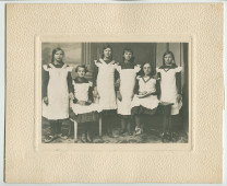 Photographie de six jeunes filles en uniforme portant leurs «remerciements à Madame et Bienfaitrice pour qu'elle accepte le dons de nos filles» – avec légende manuscrite et signatures des six filles au verso