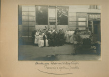 Photographie des employés de la Croix Blanche polonaise devant l'entrée des magasins de Varsovie (probablement situés dans le quartier de Wilanów), avec voiture et chauffeur (transportant vraisemblablement Mme Rembielin?ska